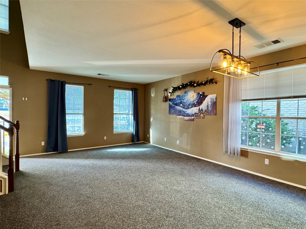 14605 Staked Plains Loop Austin, TX 78717 - Photo 6 of 30 Carpeted empty room with plenty of natural light and a chandelier