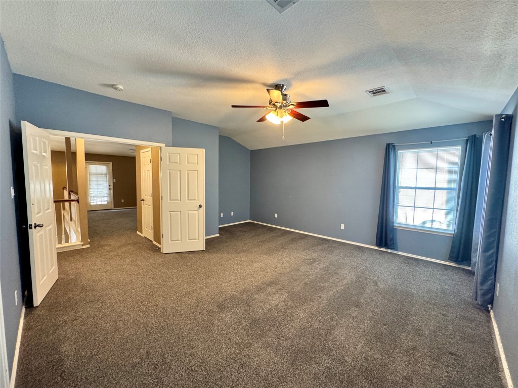 14605 Staked Plains Loop Austin, TX 78717 - Photo 9 of 30 Unfurnished bedroom featuring lofted ceiling, a textured ceiling, dark colored carpet, and a ceiling fan