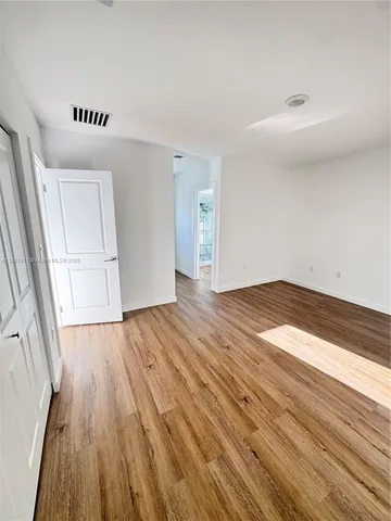 a view of an empty room with wooden floor and window