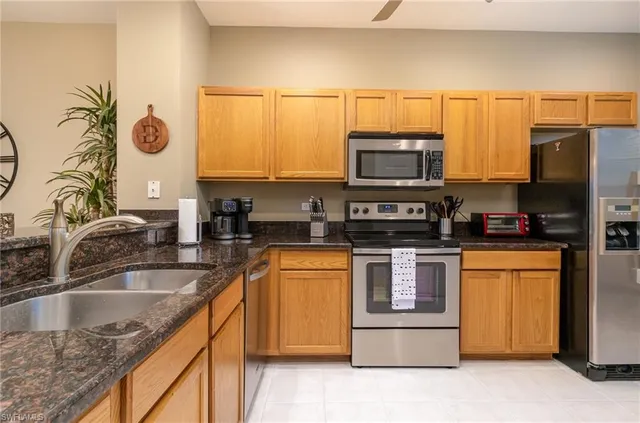 a kitchen with stainless steel appliances granite countertop a sink a stove a microwave a refrigerator and cabinets