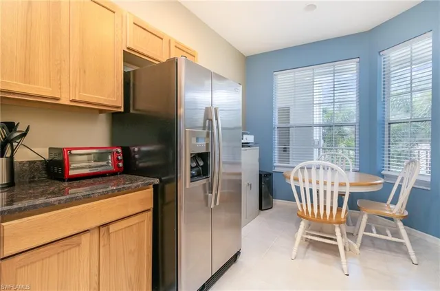 a kitchen with stainless steel appliances granite countertop a table chairs and a refrigerator