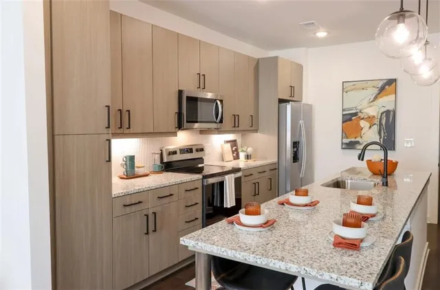 a kitchen with stainless steel appliances granite countertop a stove a refrigerator a sink a dining table and chairs