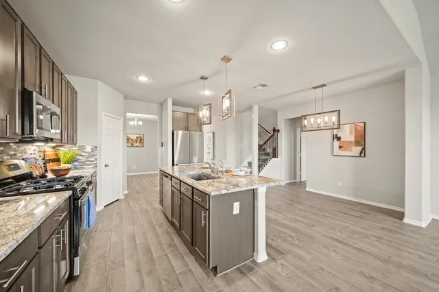a kitchen with granite countertop stainless steel appliances a sink stove top oven and cabinets