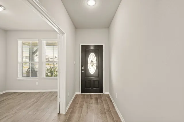 an empty room with wooden floor cabinet and windows