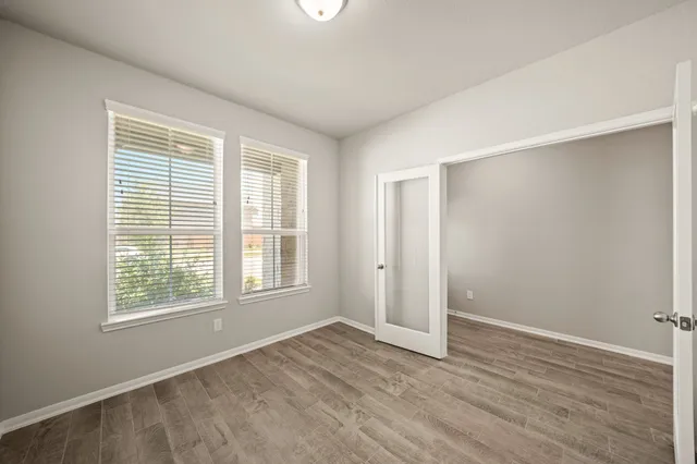 a view of an empty room with wooden floor and a window