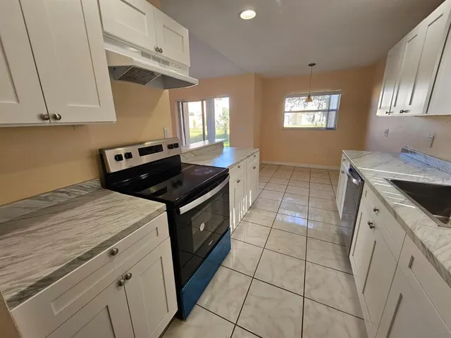 a kitchen with a sink a stove cabinets and a window