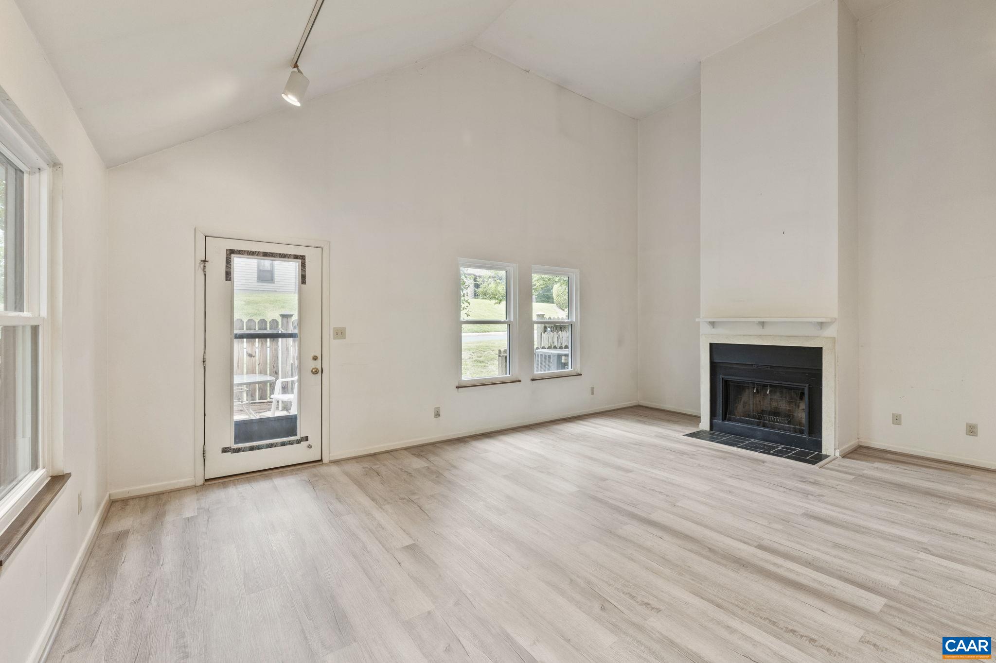 an empty room with windows a fireplace and wooden floor