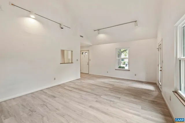 an empty room with wooden floor and windows
