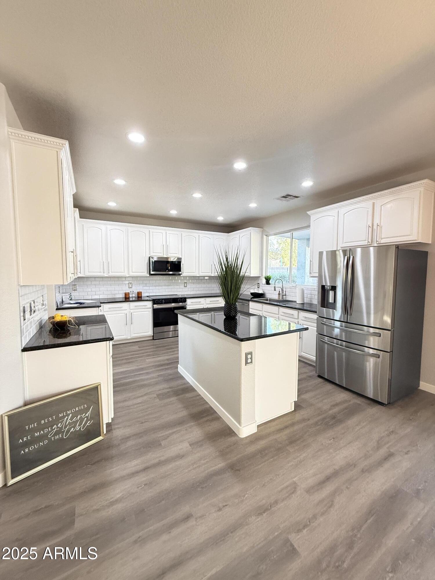 a kitchen with stainless steel appliances kitchen island granite countertop a refrigerator and a stove