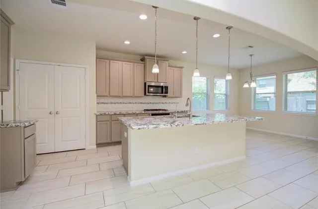 a large kitchen with granite countertop a stove a sink and a refrigerator