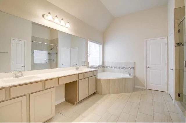 a spacious bathroom with a tub double sink and mirror