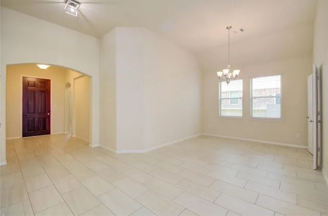 an empty room with chandelier fan and windows