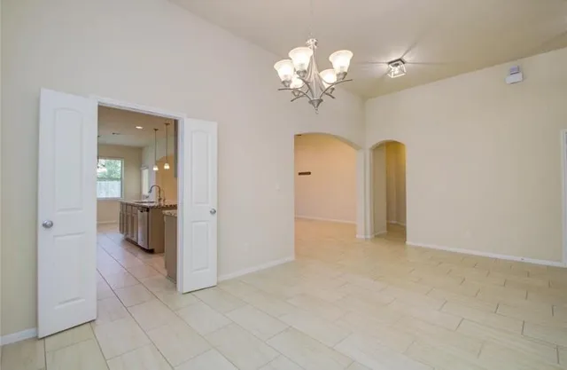 an empty room with chandelier and stainless steel appliances