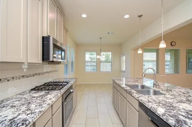 a kitchen with granite countertop a sink stove and cabinets