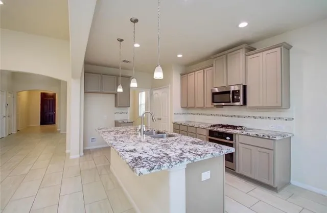 a kitchen with kitchen island granite countertop a stove and a sink