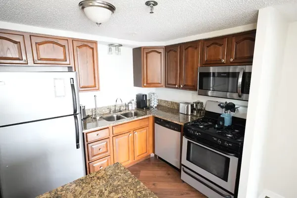 a kitchen with granite countertop a refrigerator stove top oven and sink