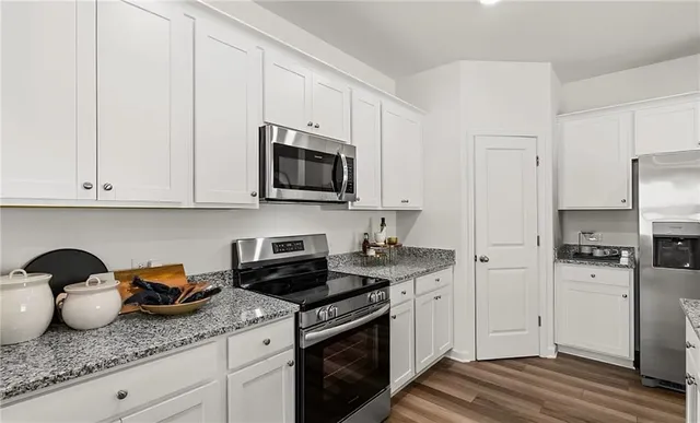 a kitchen with granite countertop white cabinets and stainless steel appliances