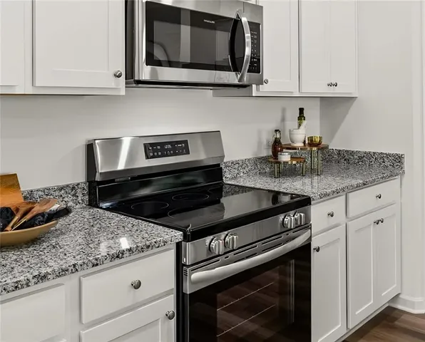 a kitchen with granite countertop white cabinets and stainless steel appliances
