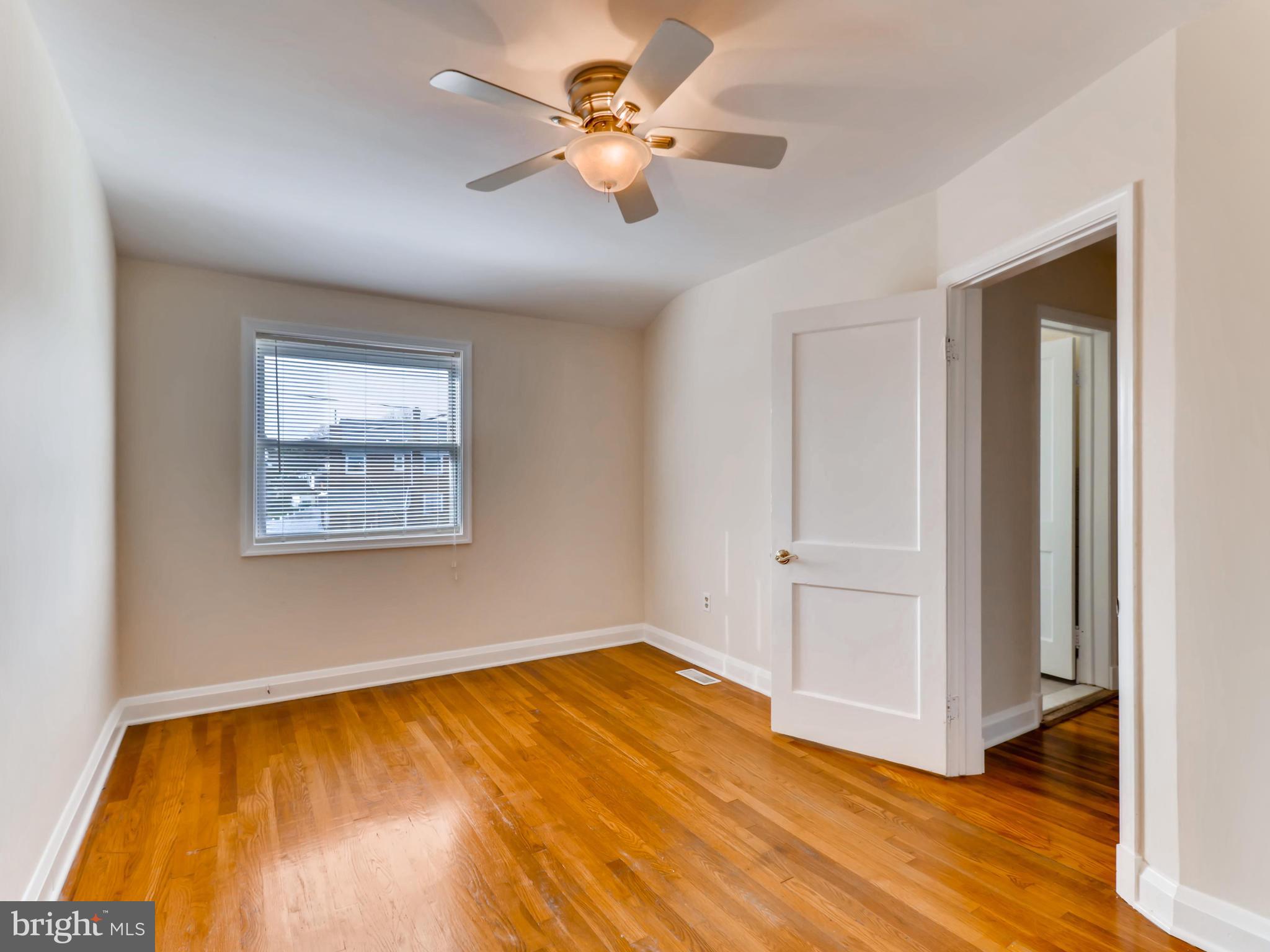 7915 Kavanagh Road Baltimore, MD 21222 - Photo 8 of 12 a view of an empty room with window and wooden floor
