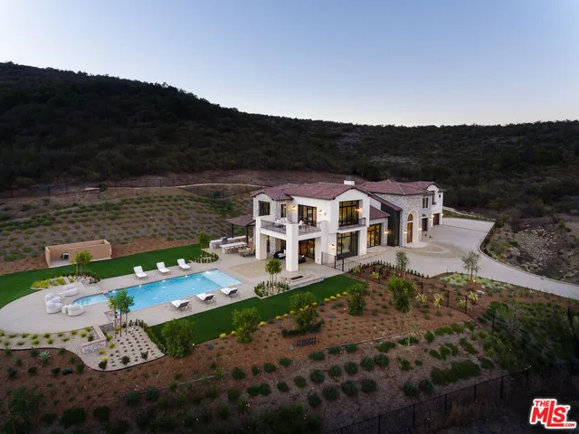 a view of a white house with a big yard and large trees