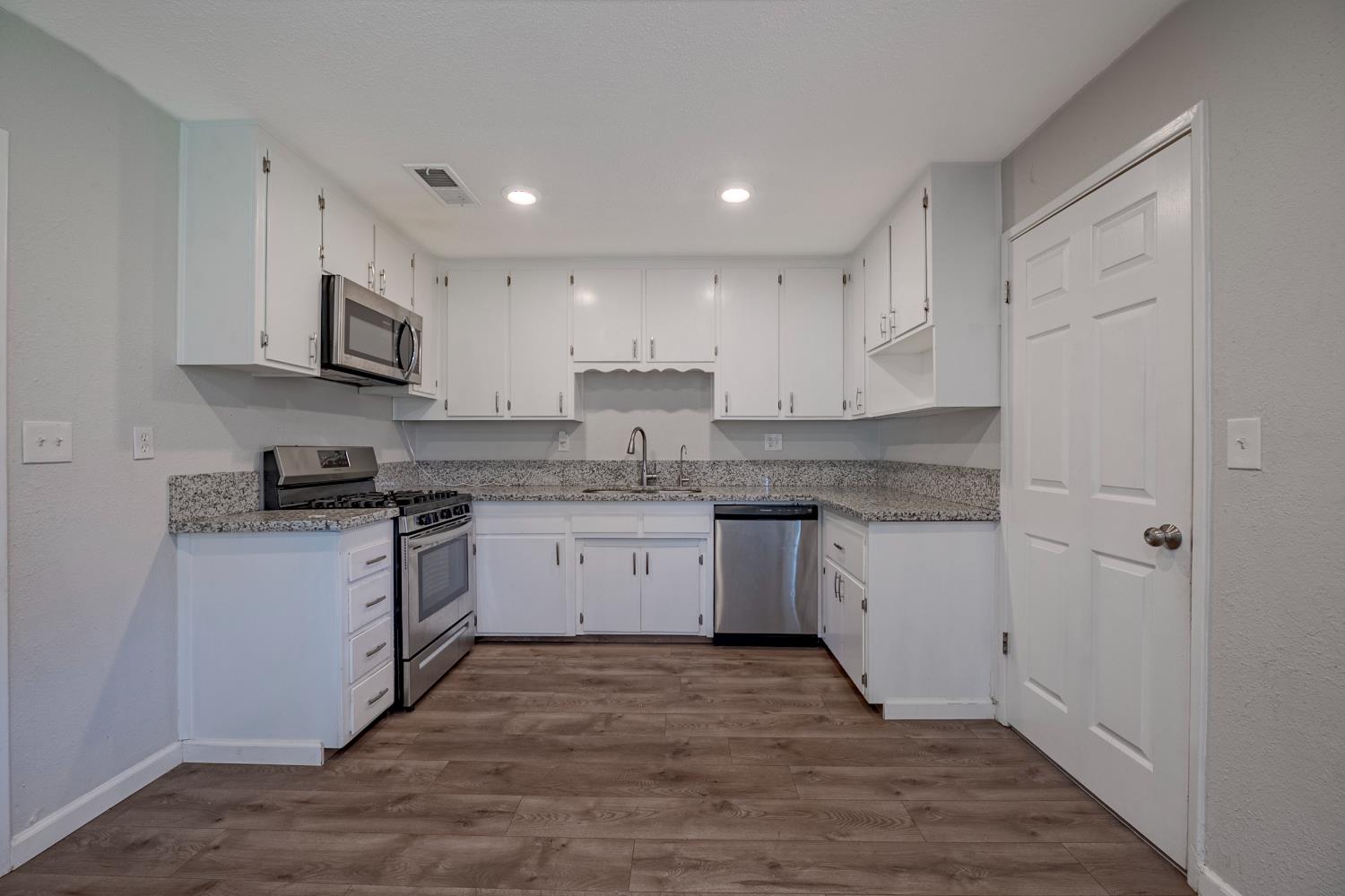 3085 North Buhach Road Atwater, CA 95301 - Photo 29 of 40 a kitchen with stainless steel appliances granite countertop a stove top oven a sink and white cabinets
