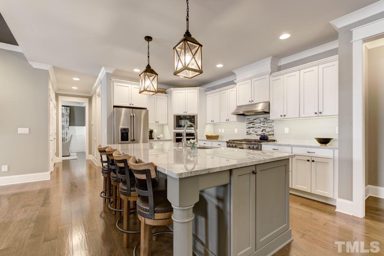 1003 Collins Drive Raleigh, NC 27609 - Photo 4 of 25 Continue into the gourmet kitchen that offers Miele stainless steel appliances, granite counters, a huge center island with seating, cabinets with crown and under-mount lights, and a decorative tile backsplash.