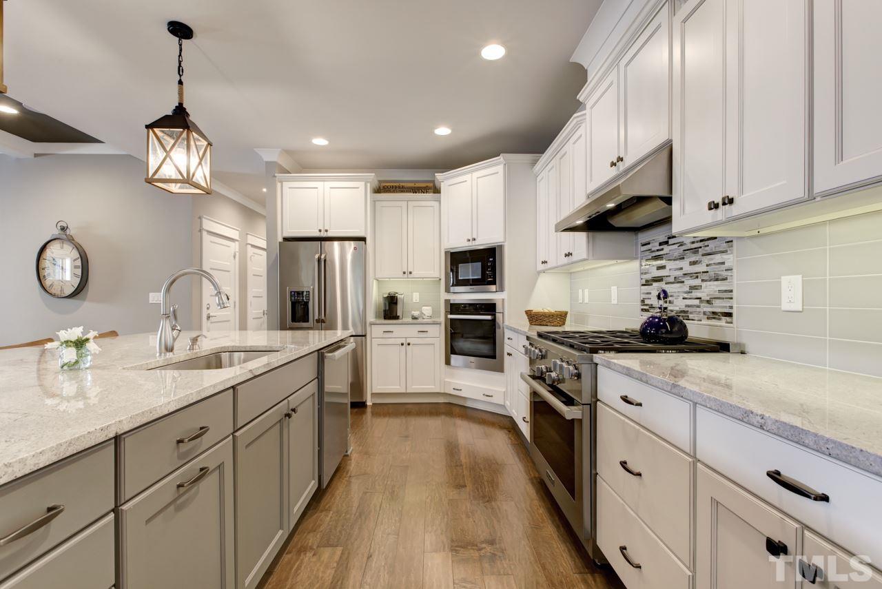 1003 Collins Drive Raleigh, NC 27609 - Photo 5 of 25 Continue into the gourmet kitchen that offers Miele stainless steel appliances, granite counters, a huge center island with seating, cabinets with crown and under-mount lights, and a decorative tile backsplash.