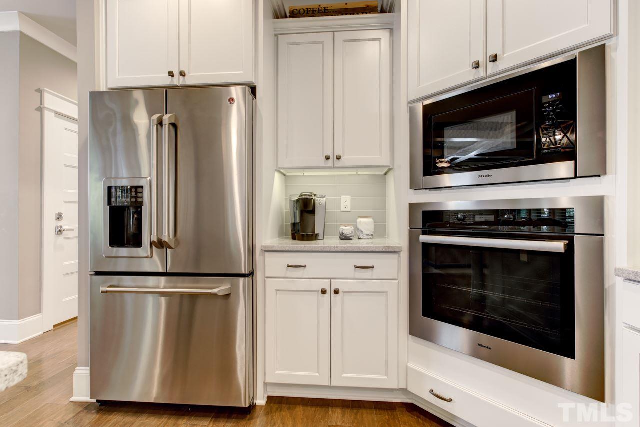1003 Collins Drive Raleigh, NC 27609 - Photo 7 of 25 Continue into the gourmet kitchen that offers Miele stainless steel appliances, granite counters, a huge center island with seating, cabinets with crown and under-mount lights, and a decorative tile backsplash.