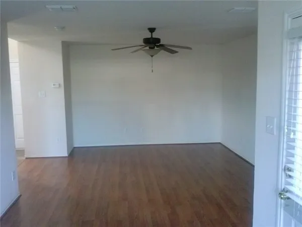 a view of a room with wooden floor and a ceiling fan