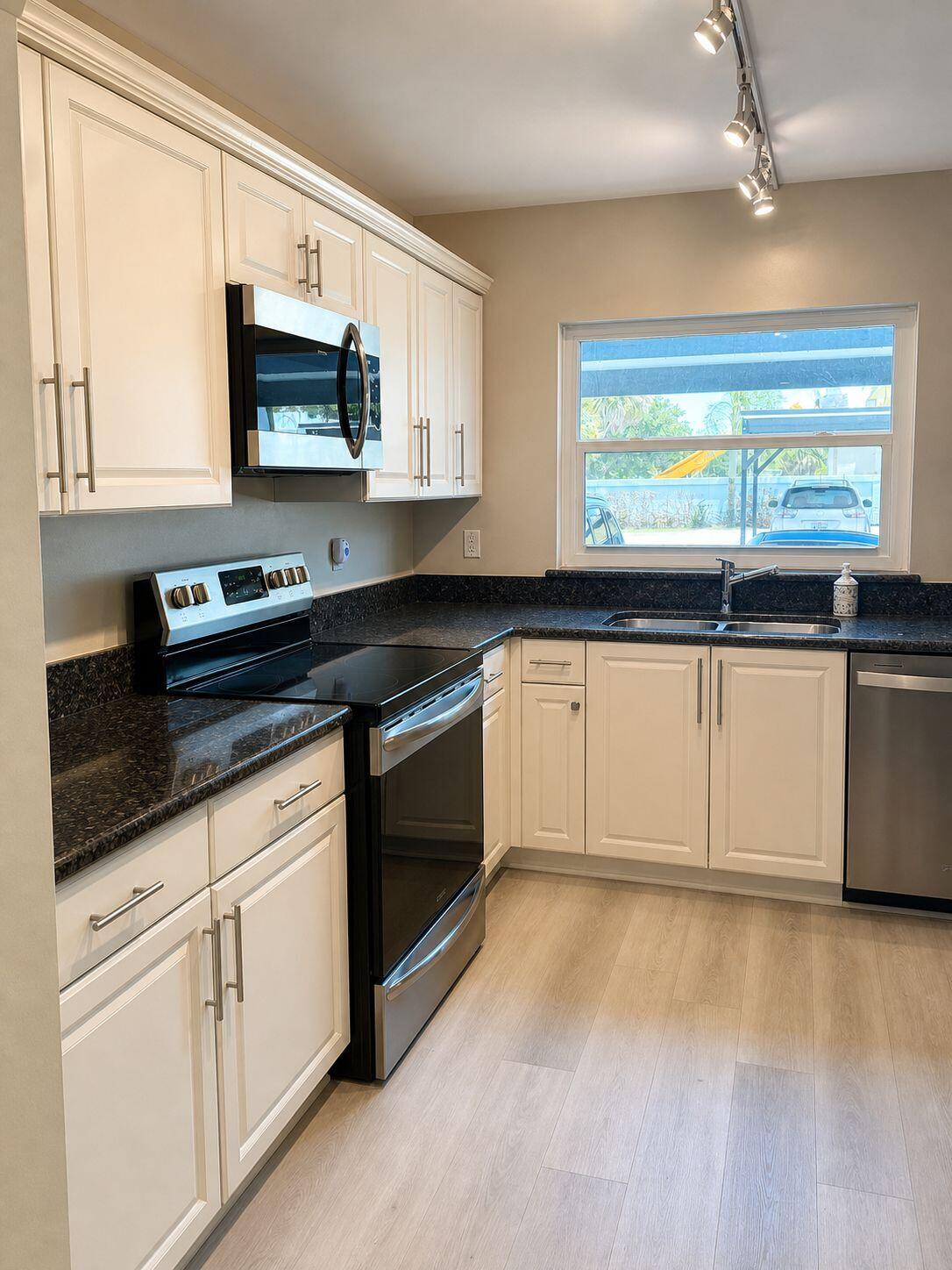 1871 Southwest Palm City Road, Unit G401 Stuart, FL 34994 - Photo 1 of 16 a kitchen with granite countertop white cabinets and white appliances