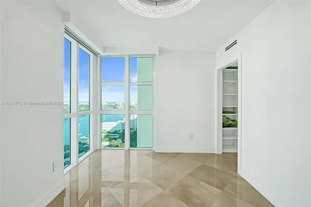 a view of a livingroom with a large window and potted plants