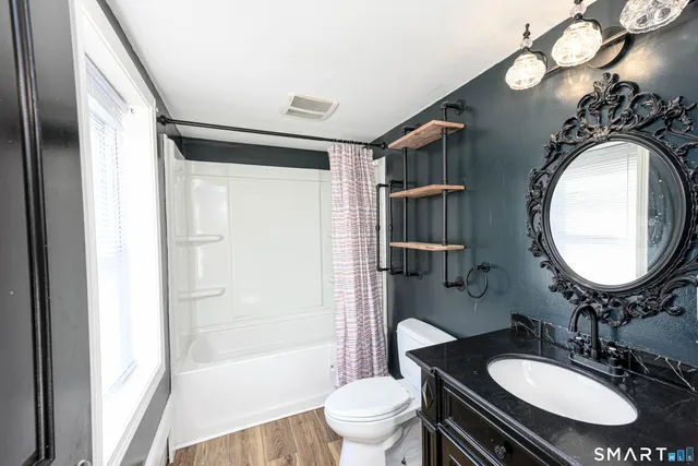 a bathroom with a sink a toilet a mirror and shower