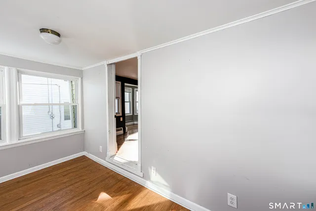 a view of an empty room with wooden floor and a window
