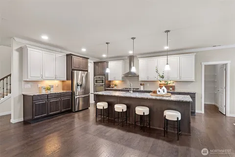 a large kitchen with kitchen island a large counter top and stainless steel appliances