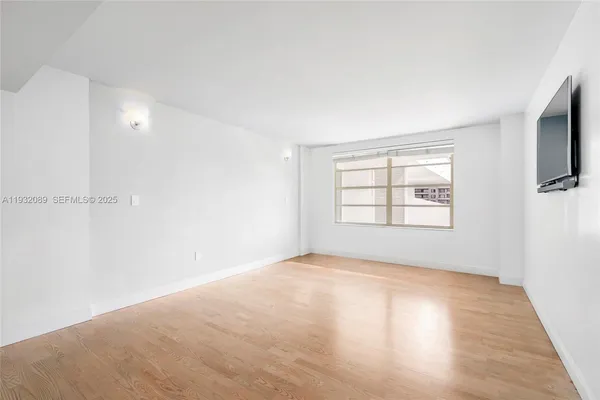 a view of an empty room with a window and wooden floor