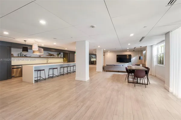 a living room with stainless steel appliances furniture and a kitchen view
