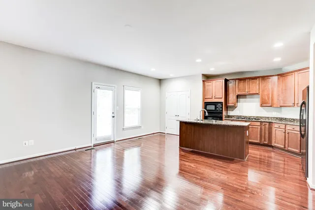 a kitchen with stainless steel appliances granite countertop a refrigerator a sink dishwasher a stove and a large countertops with wooden floor