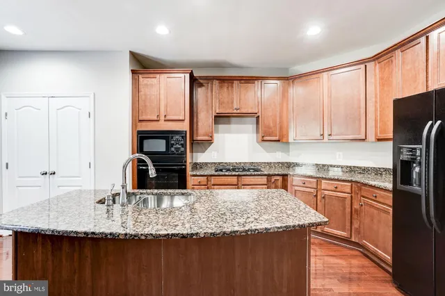 a kitchen with granite countertop a sink a counter top space cabinets and stainless steel appliances