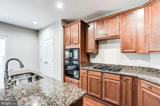 a kitchen with stainless steel appliances granite countertop a stove a sink and a refrigerator with wooden cabinets