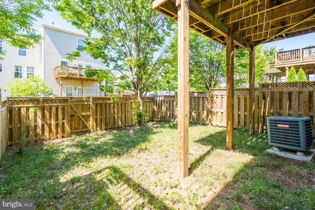 a view of a backyard with wooden fence and large trees