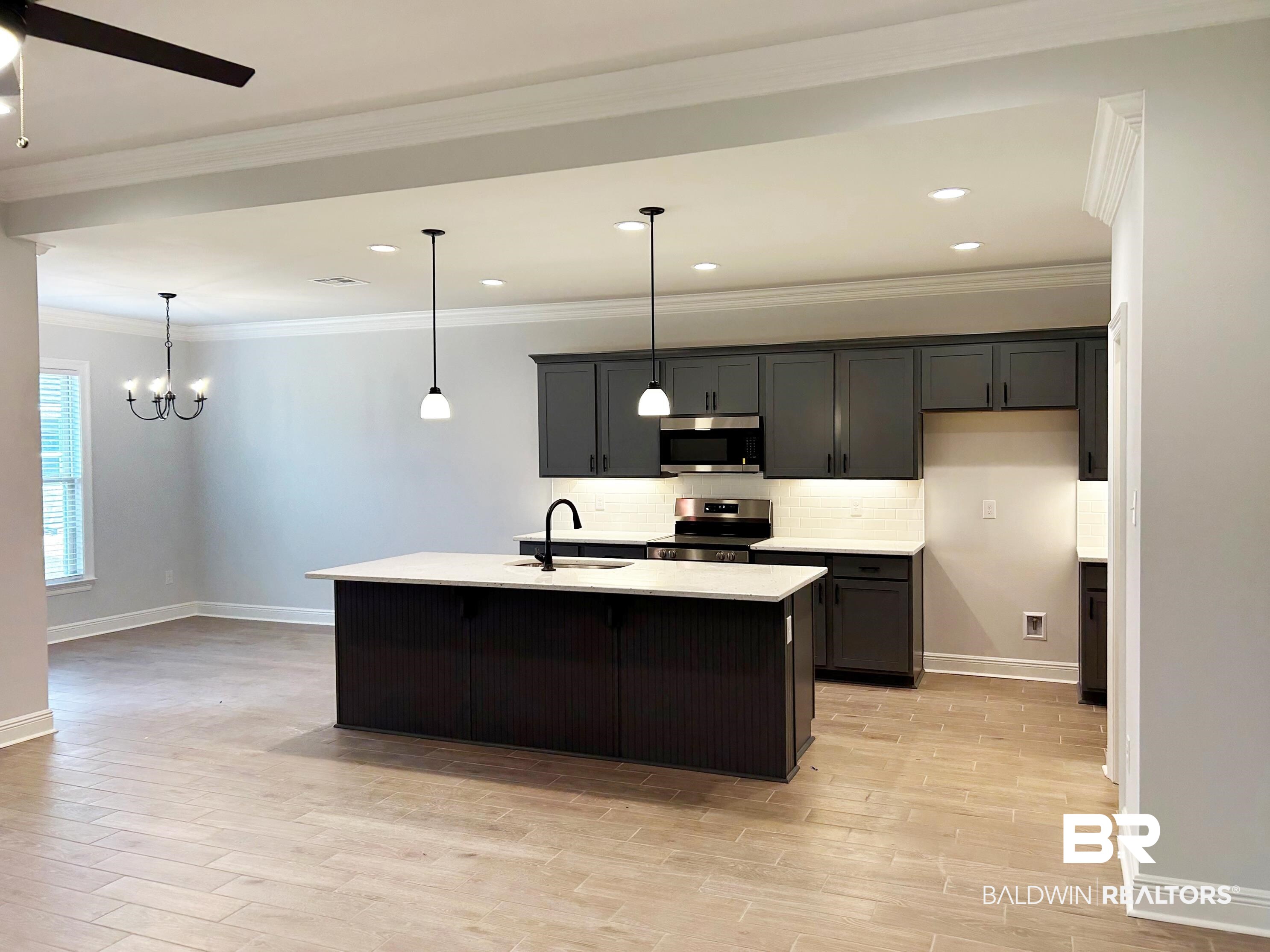 869 Sumter Loop Foley, AL 36535 - Photo 8 of 24 Kitchen featuring stainless steel appliances, hanging light fixtures, crown molding, a center island with sink, and light wood-style flooring