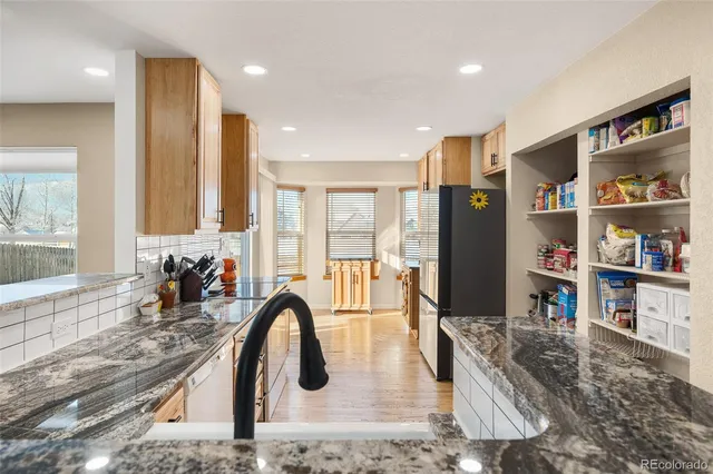 a kitchen with stainless steel appliances granite countertop a refrigerator a stove and a sink with wooden floor