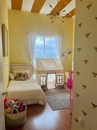 a bedroom with a bed and a dresser with wooden floor