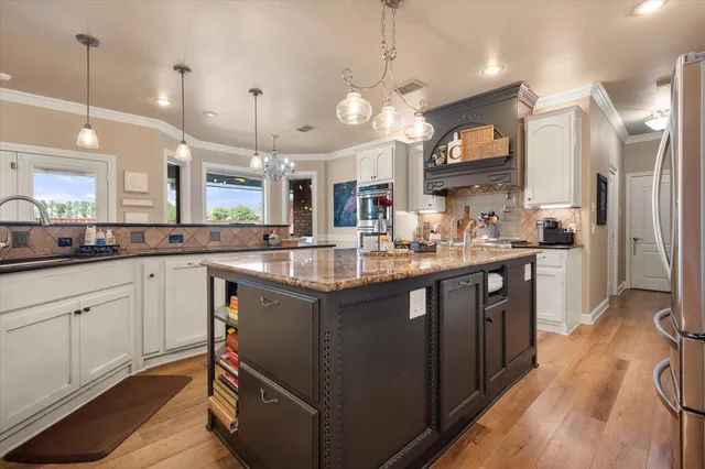 a kitchen with stainless steel appliances granite countertop a sink dishwasher and refrigerator with wooden floor