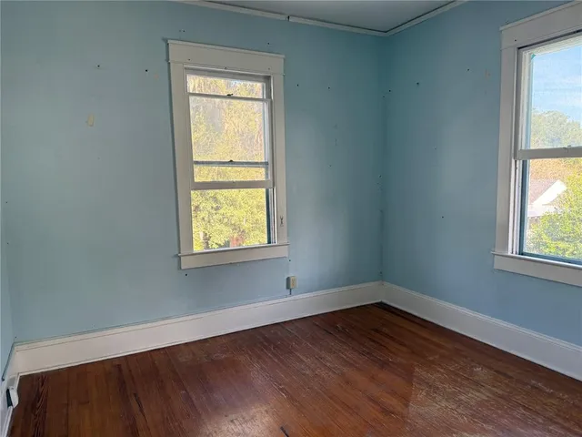 a view of an empty room with wooden floor and a window