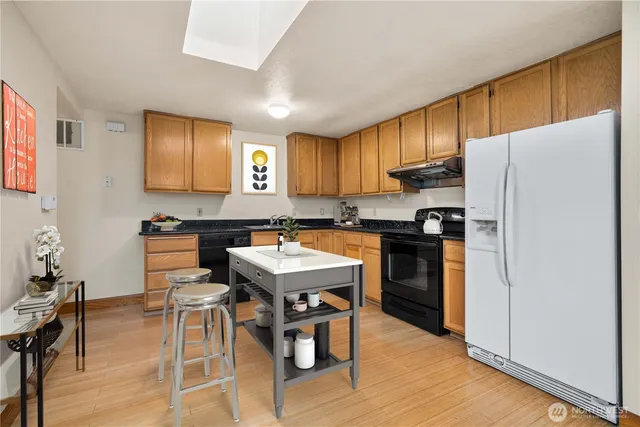 a kitchen with a refrigerator a stove a sink dishwasher with a dining table and chair with wooden floor