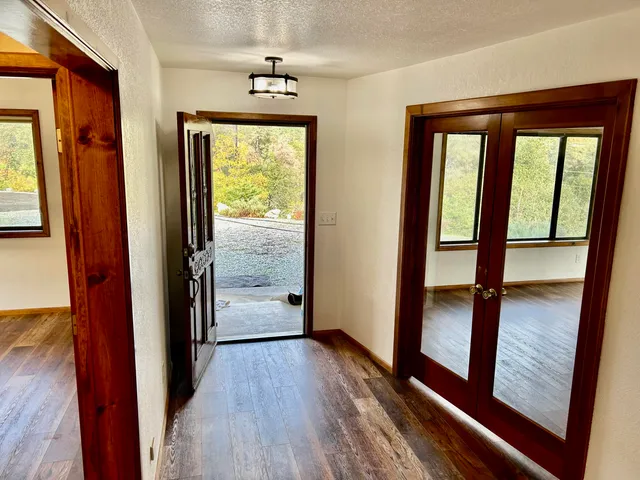 a view of an empty room with windows and chandelier fan