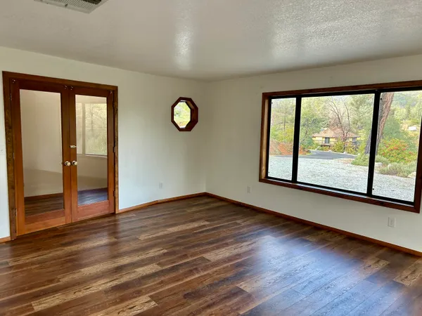 a view of empty room with wooden floor and floor to ceiling window