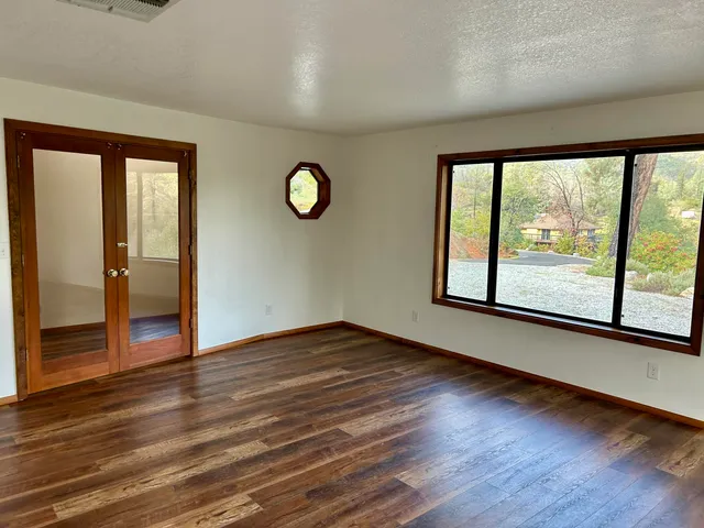 a view of empty room with wooden floor and floor to ceiling window