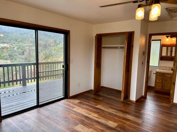 a view of empty room with wooden floor and fan